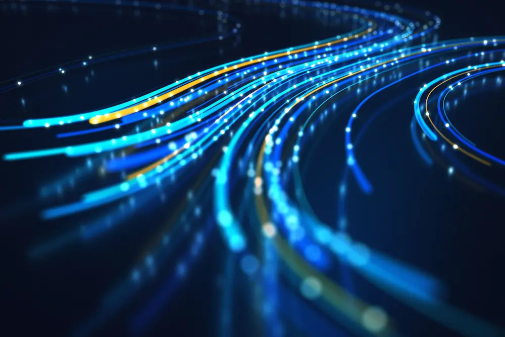 Timelapse image of lights blurring into colorful, winding lines on a curved highway.