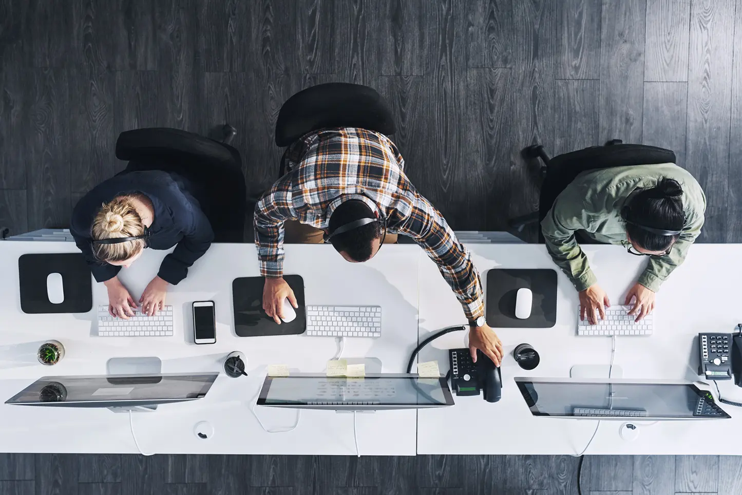 Photo showing row of people working on computers, viewed from above.