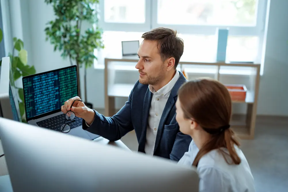 Photo of coworkers talking while viewing computer screen.