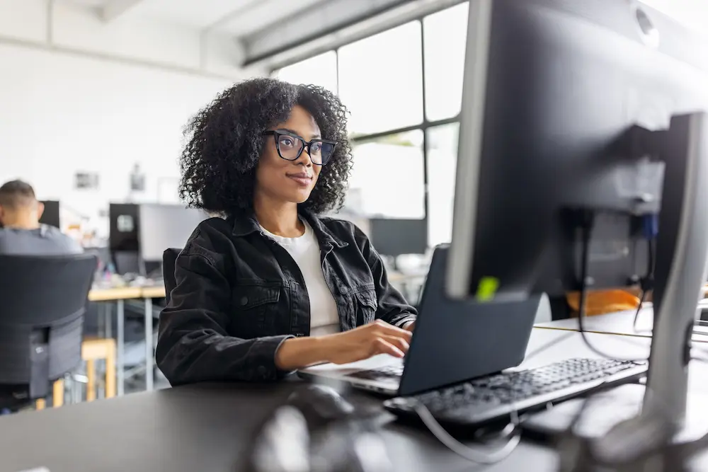 Woman working on laptop computer with a cloud server backup service.
