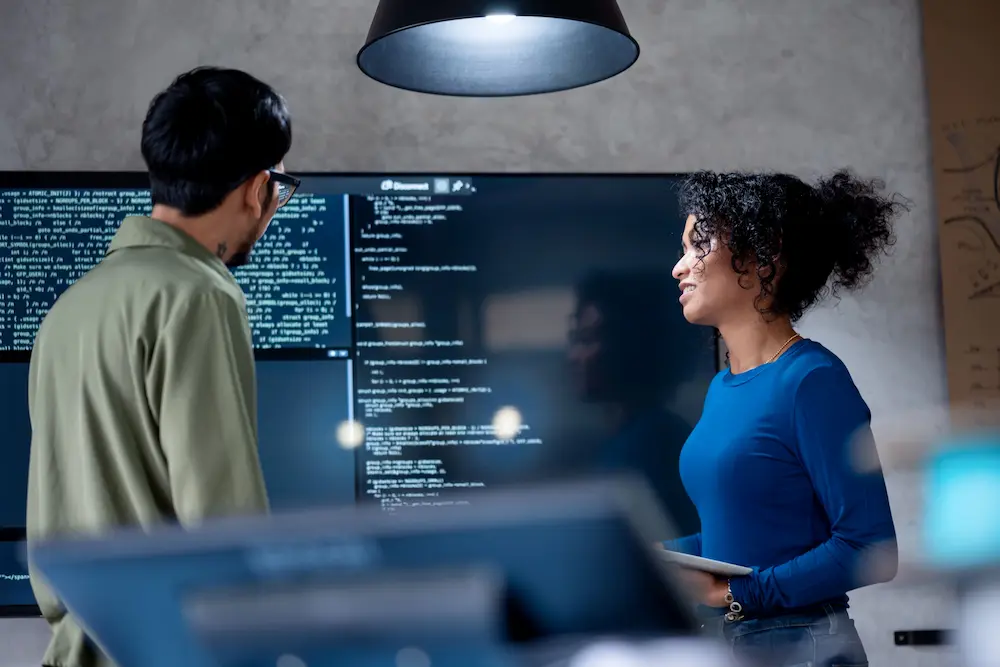 Photo of technicians viewing large computer screen.